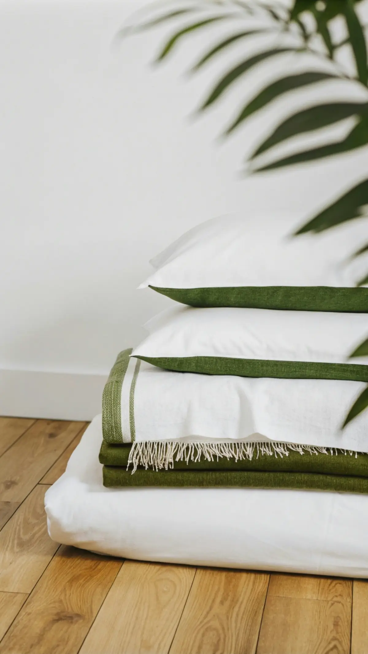 Linge de maison blanc à liseré vert plié sur un parquet