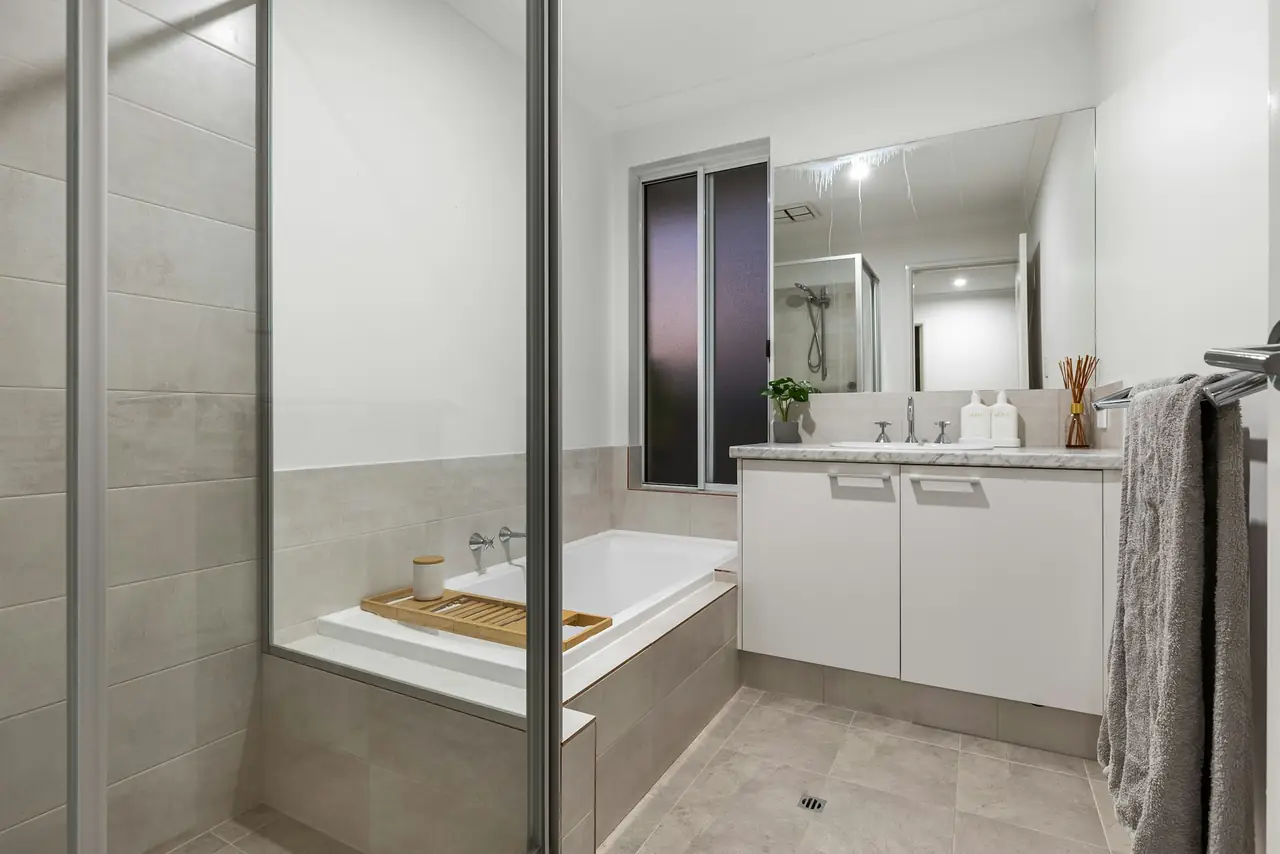 Salle de bains rénovée avec douche vitrée, baignoire et meuble vasque clair